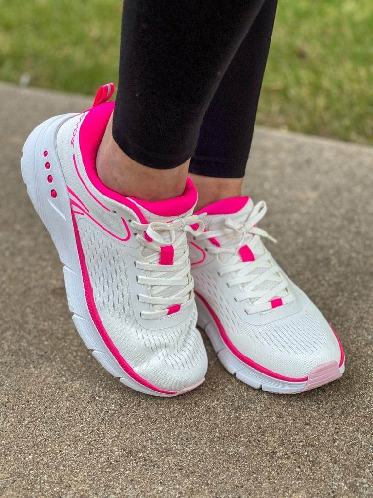 women's feet in black leggings wearing easy spirit emove sneakers in pink and white