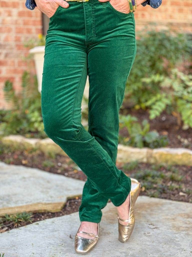 woman wearing green velvet jeans and gold mary jane flats