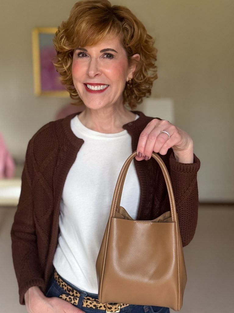 woman wearing brown cardigan and showing anthro mini hollace tote as a tote bag