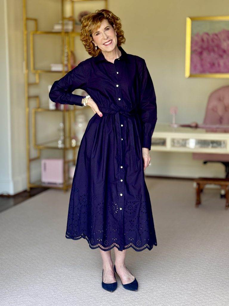 woman standing with one hand on hip in an office wearing blue dress