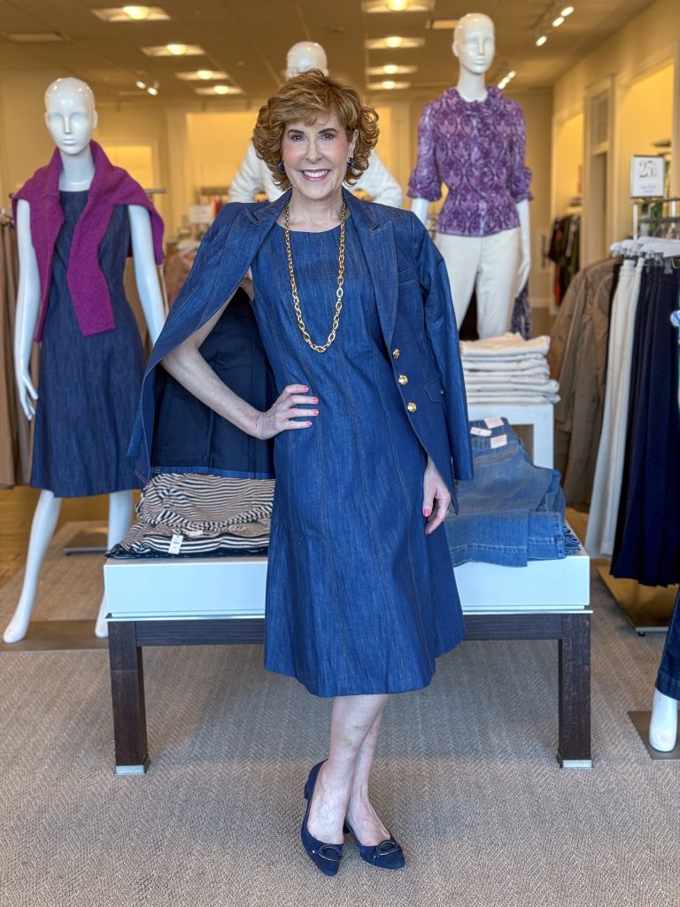 woman wearing denim dress with denim blazer over shoulders standing in a talbots store