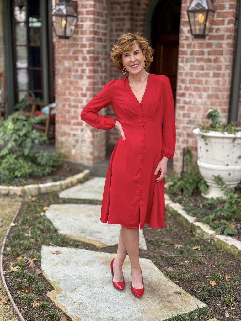 woman standing in front yard wearing red dress posing and looking into camera