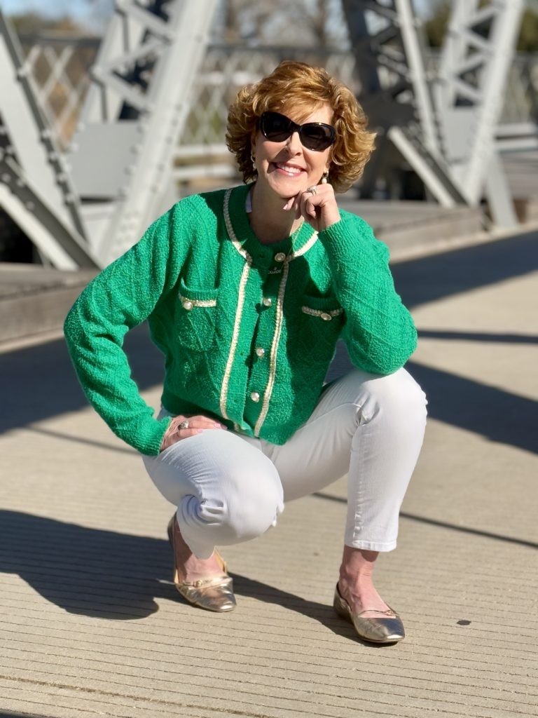 Woman crouching on a bridge wearing a ladylike cardigan in kelly green