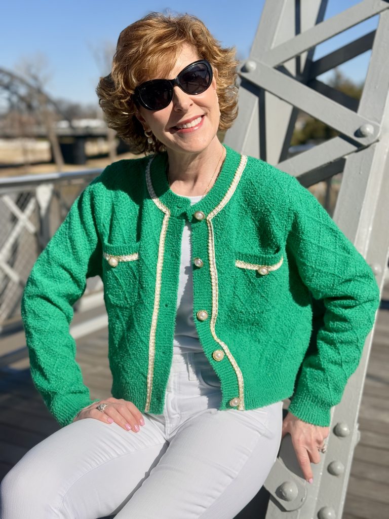 woman sitting on a bridge trestle wearing a green cardigan