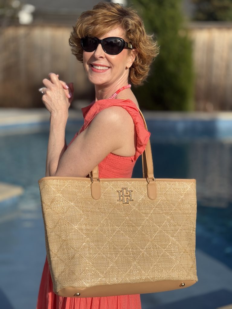 woman standing by a pool wearing a shoulder tote by caroline hill/carla covington