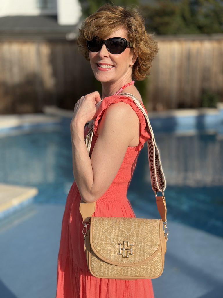 woman standing by a pool wearing a shoulder bag by caroline hill/carla covington