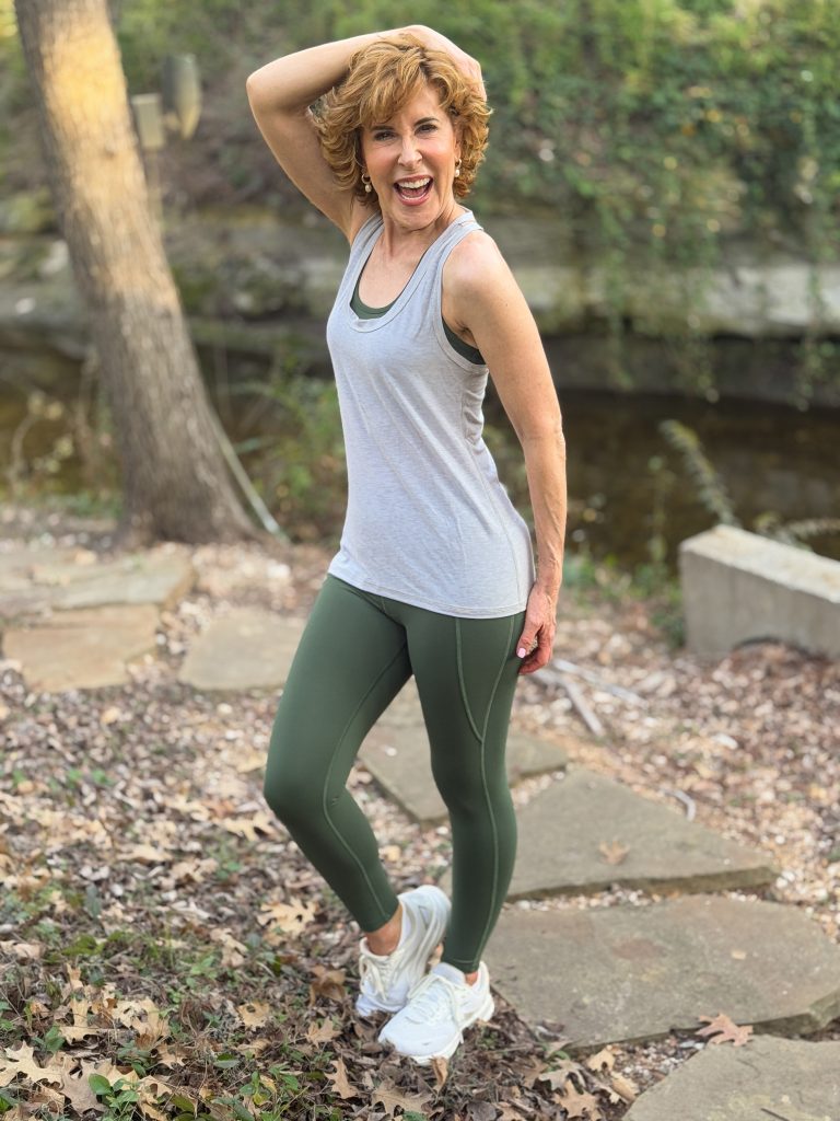 woman standing in a wooded area wearing definite articles non toxic leggings, sports bra, and tank top