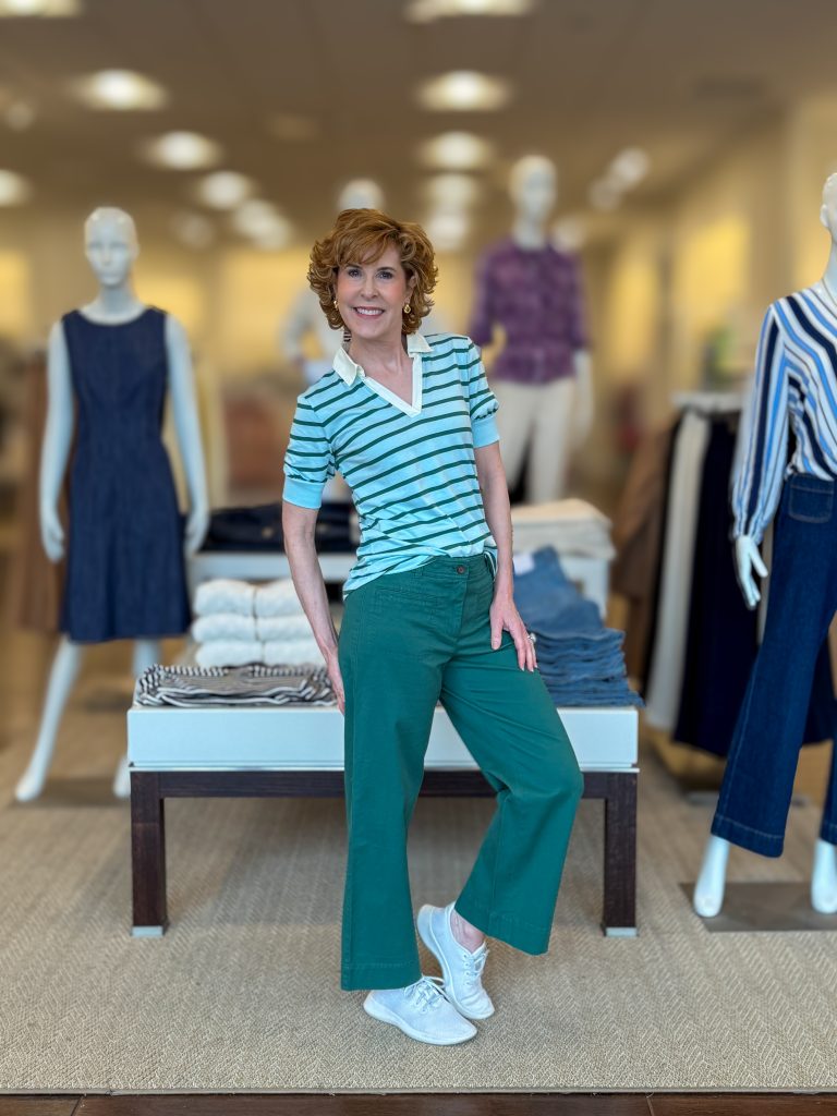 woman over 50 posing in a store wearing polo style top and green twill pants