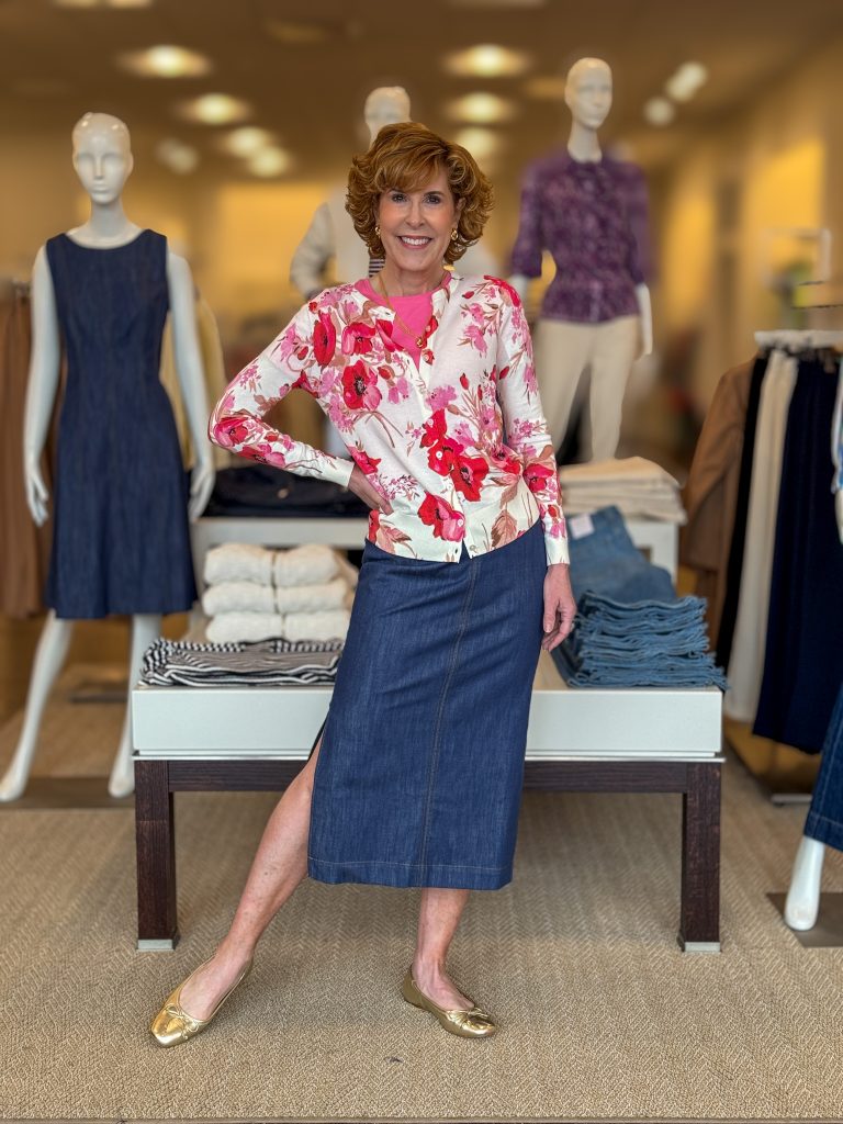 woman over 50 posing in a store wearing long denim skirt and floral print cardigan