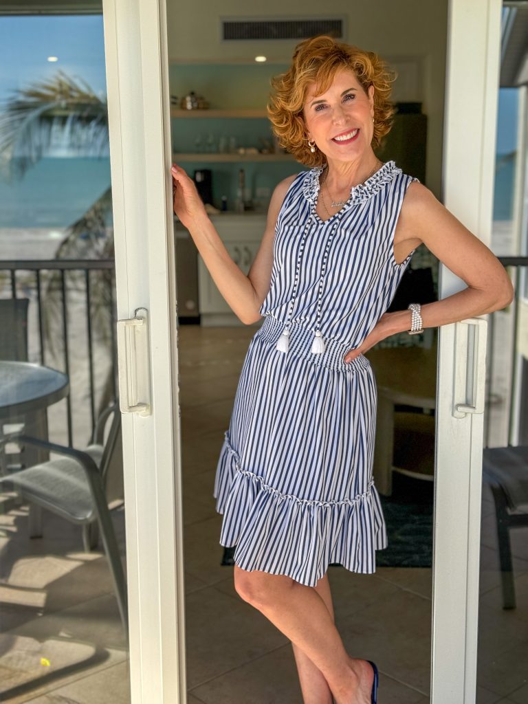 woman over 50 standing in front of sliding glass doors wearing blue and white striped UPF 50 dress