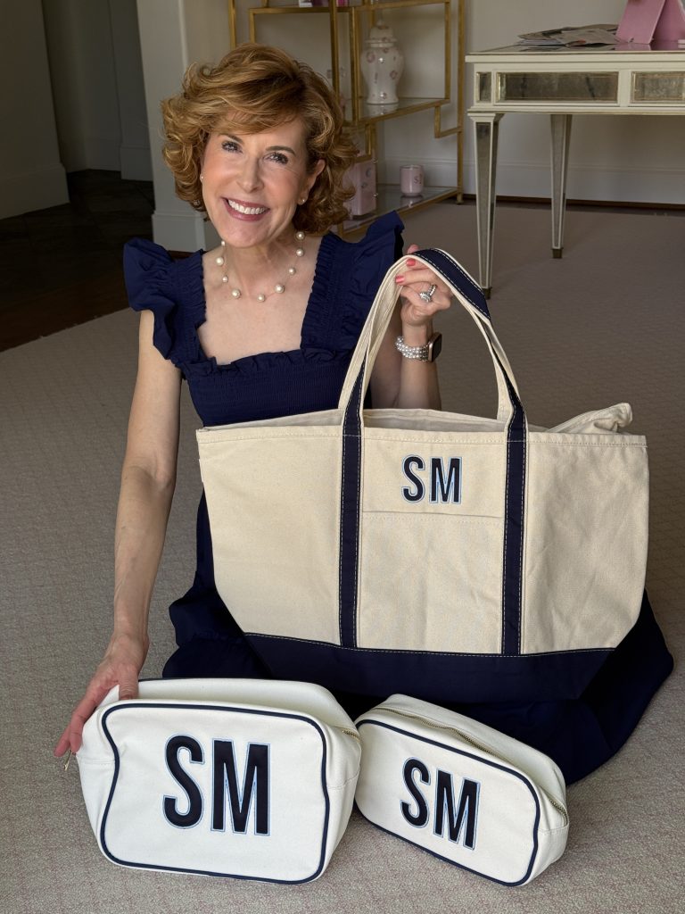 Woman over 50 wearing navy blue dress and showing applique monogram bags from Sprinkled with Pink.