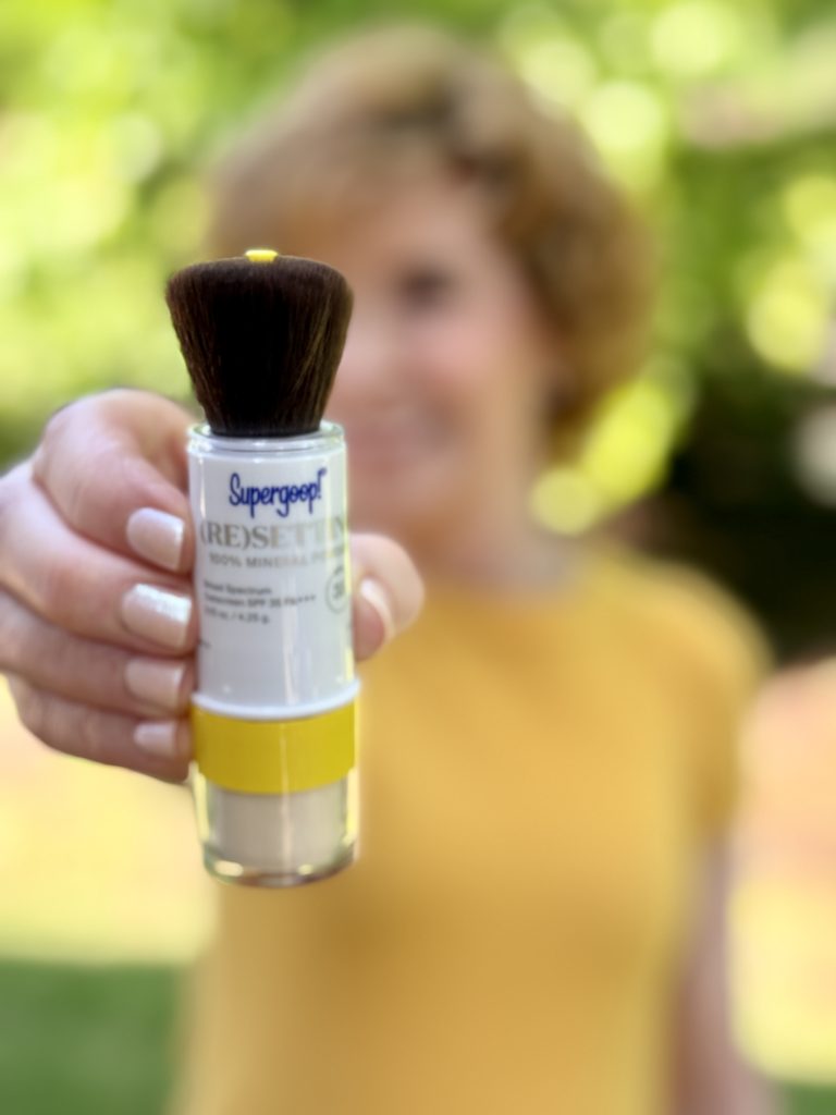 woman holding supergoop mineral powder sunscreen